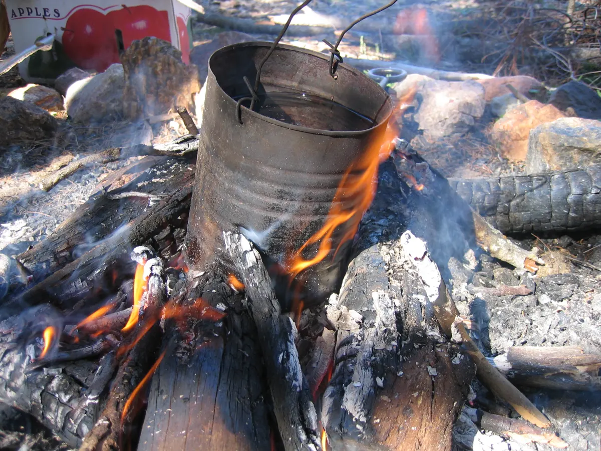A billycan heating over a campfire