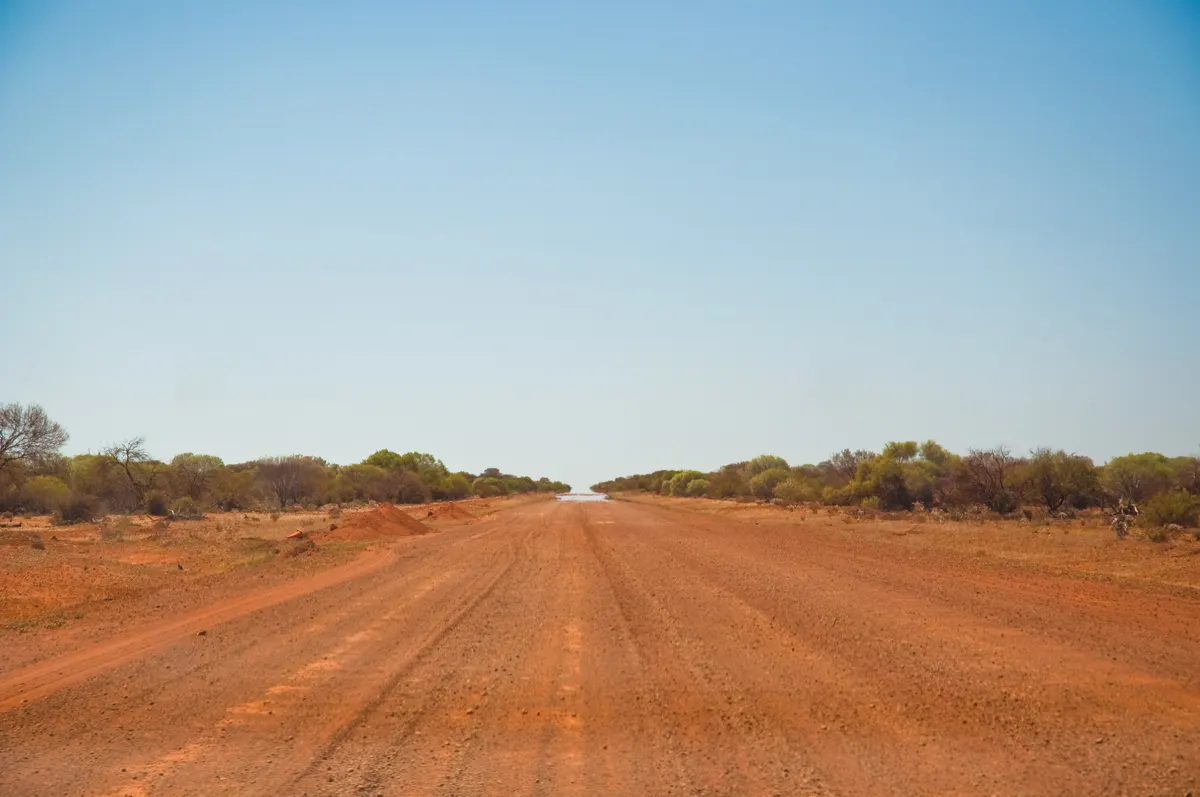 A straight red dirt road through the outback in Western Australia
